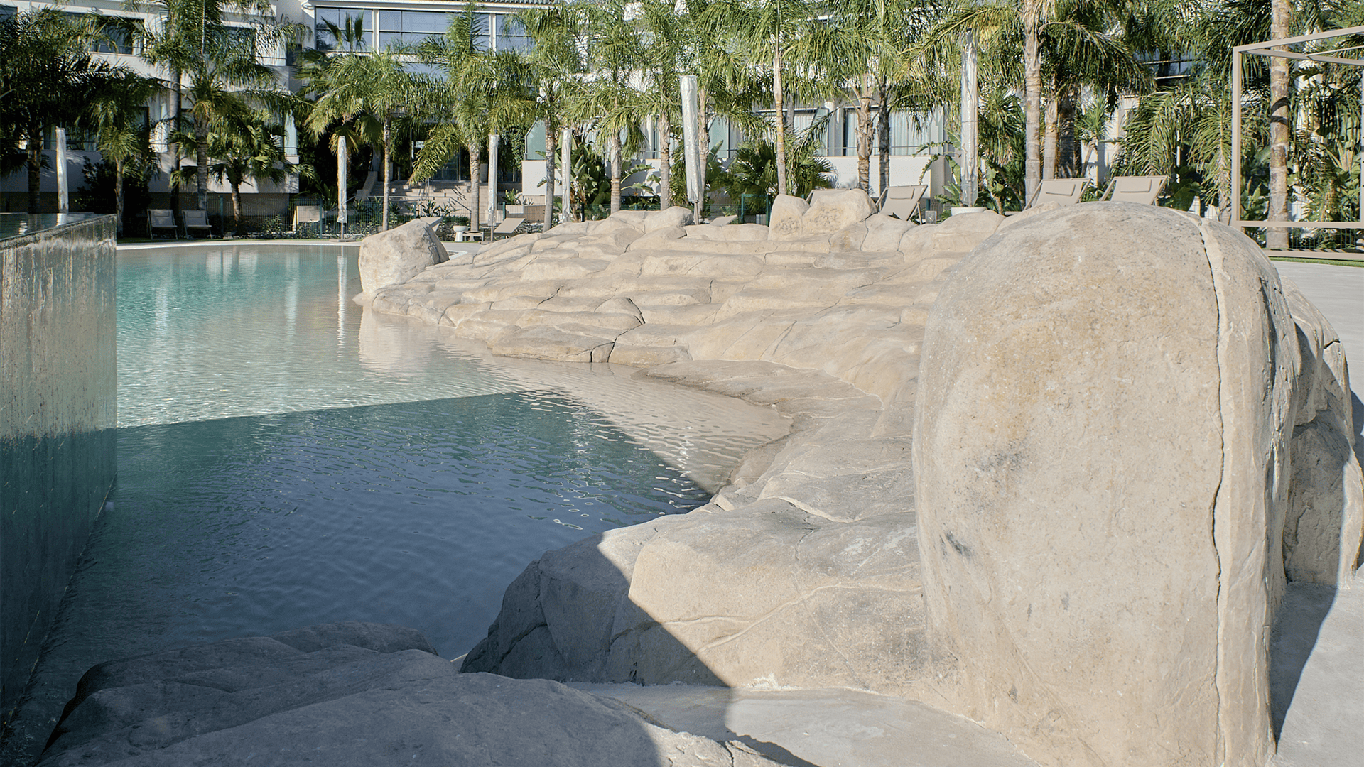Piscina de arena integrada en un entorno exterior con acabado natural